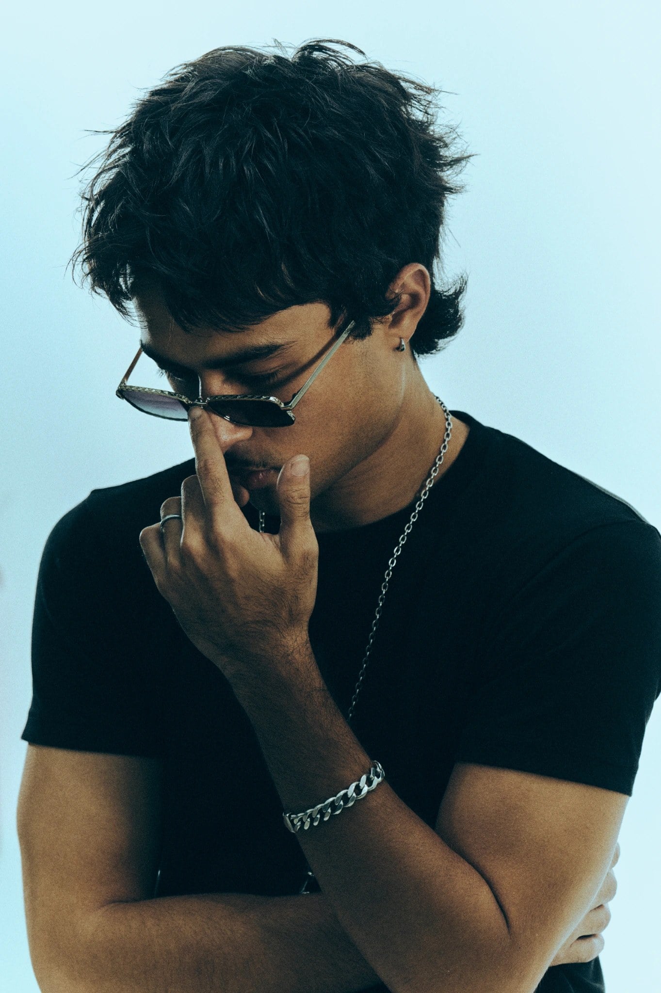 Textured mullet, head tilted down, adjusting sunglasses